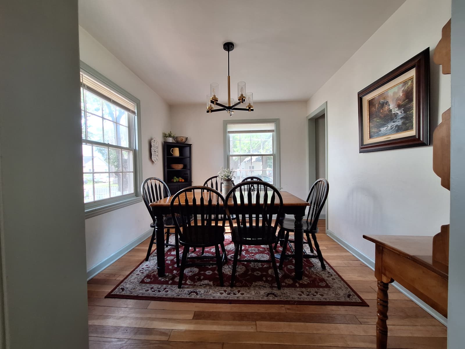 Dining room in a Cape Cod home with hardwood floors and a table set beneath a window