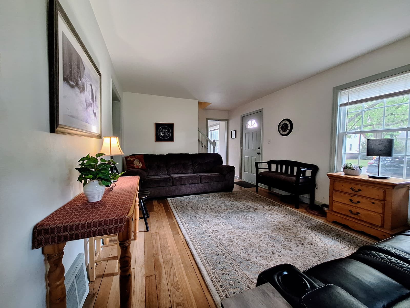 Living room with hardwood floors, a front door with an arched window and afternoon light