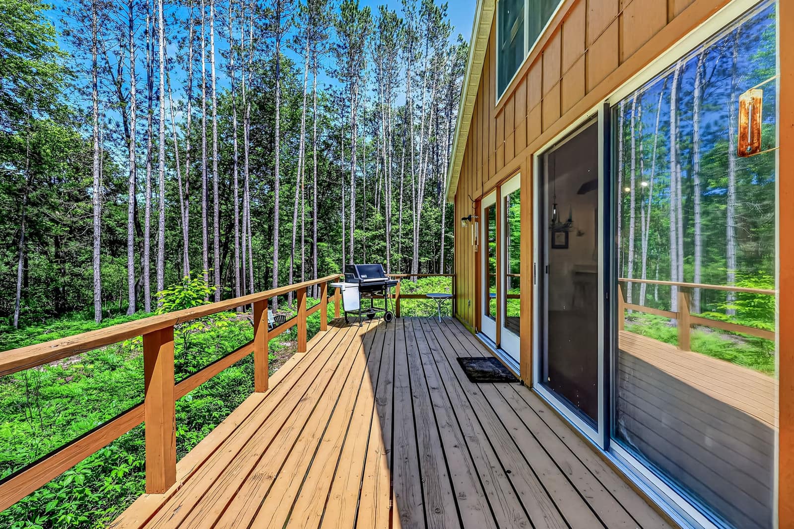 Cedar sided cabin with a wraparound deck among tall pines on a wooded Newaygo County parcel