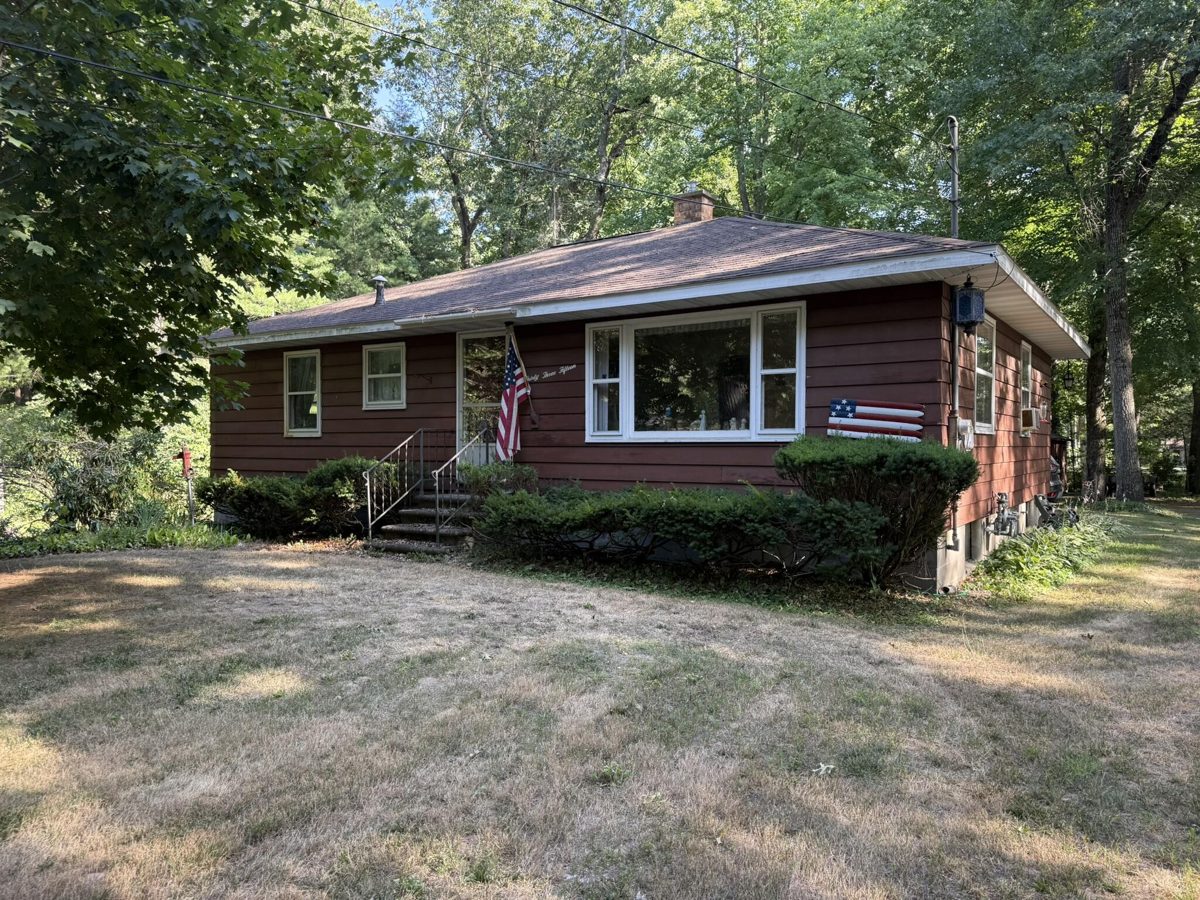 Brick ranch home with a wide front window and a flag by the porch